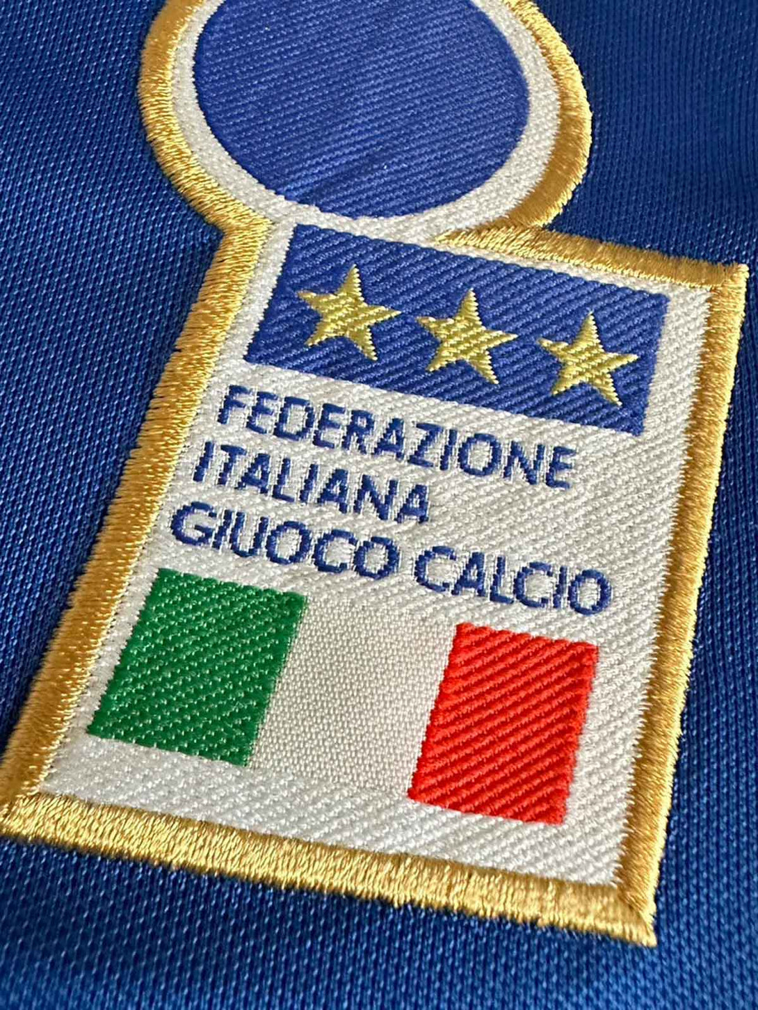 製品画像: 1996年UEFAヨーロッパ選手権 イタリア代表 ホーム ユニフォーム ピエロ14番 正面、クラシック ブルーデザイン サッカーシャツ

詳細画像: 背面のピエロ14番 手作業 フロックプリント ディテール、レトロ イタリア代表 ユニフォーム