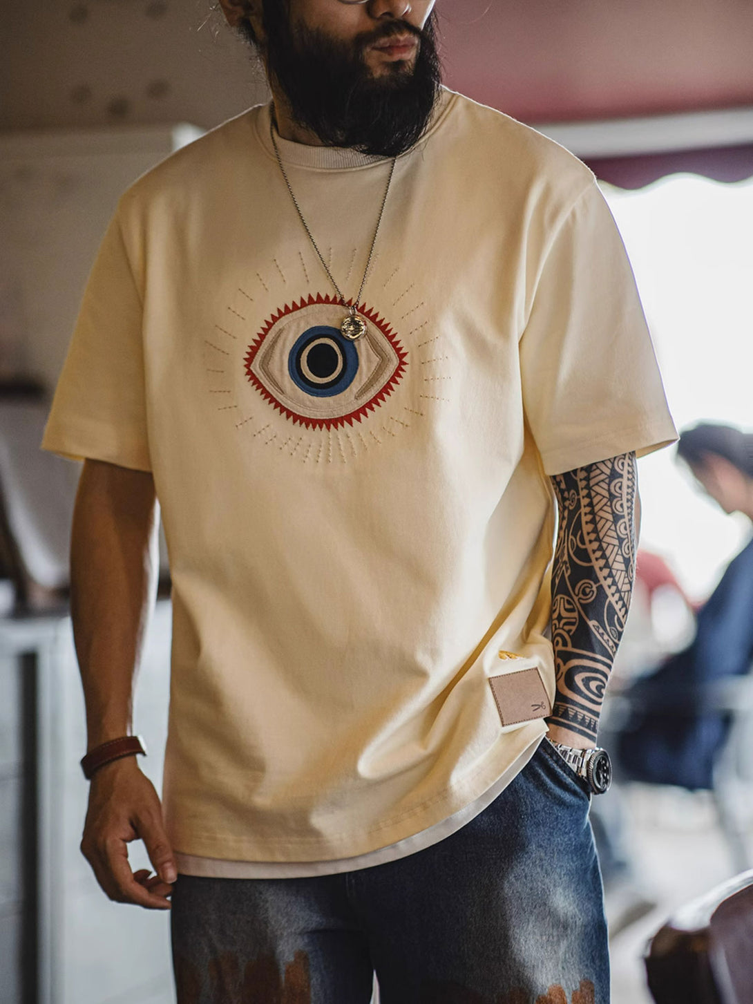 モデルが「守護の眼」ショートスリーブTシャツを着用し、そのスタイルとフィット感を披露する全身像。