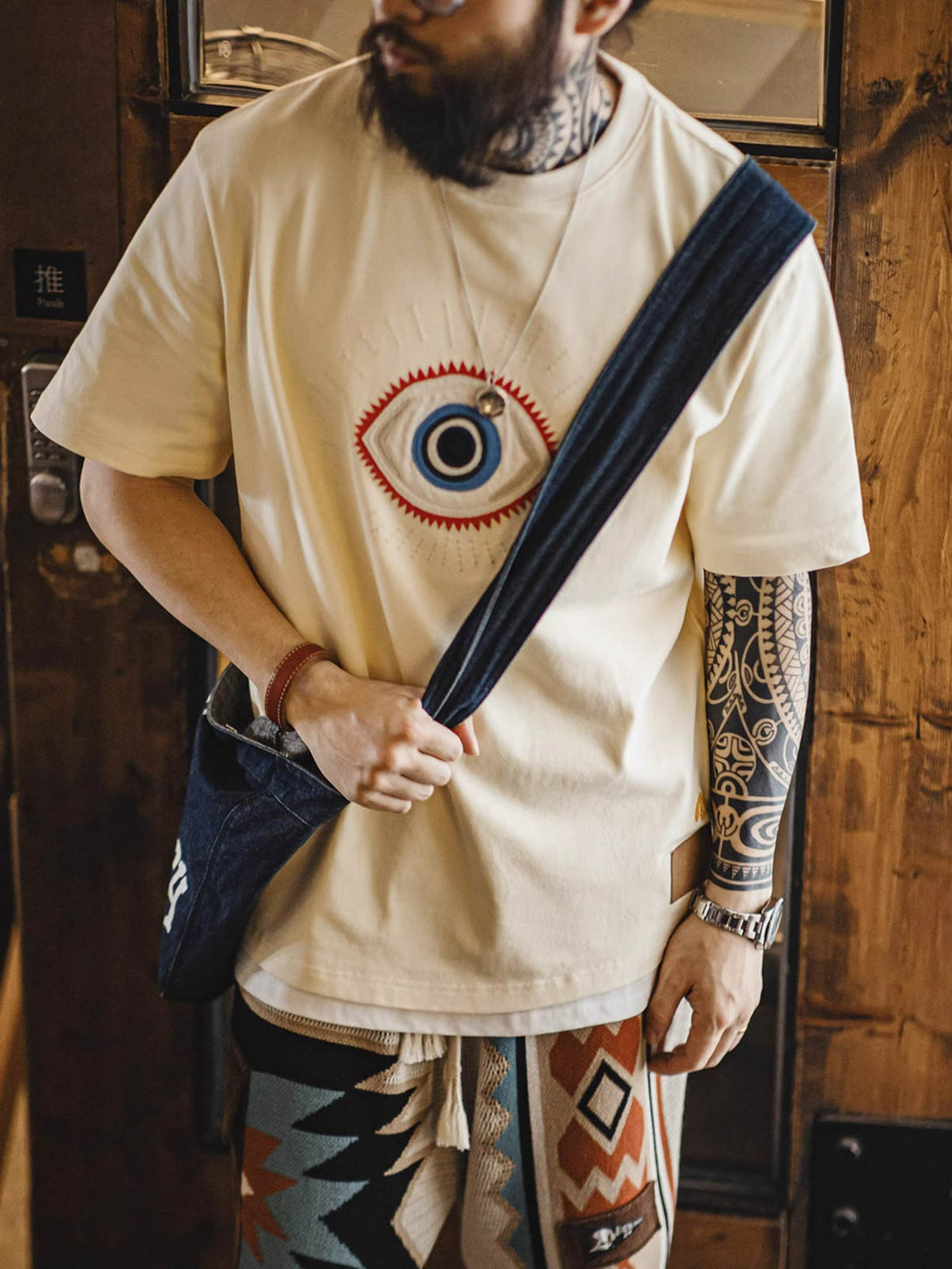 モデルが「守護の眼」ショートスリーブTシャツを着用し、そのスタイルとフィット感を披露する全身像。