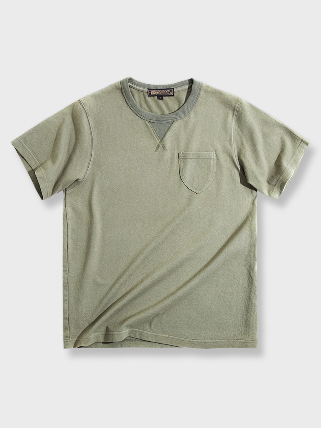 1950年代の軍服にインスパイアされたヴィンテージミリタリーグリーンのVネックポケットTシャツの全体ビュー。太いVネック補強と胸ポケットが特徴で、耐久性とスタイルを提供します。