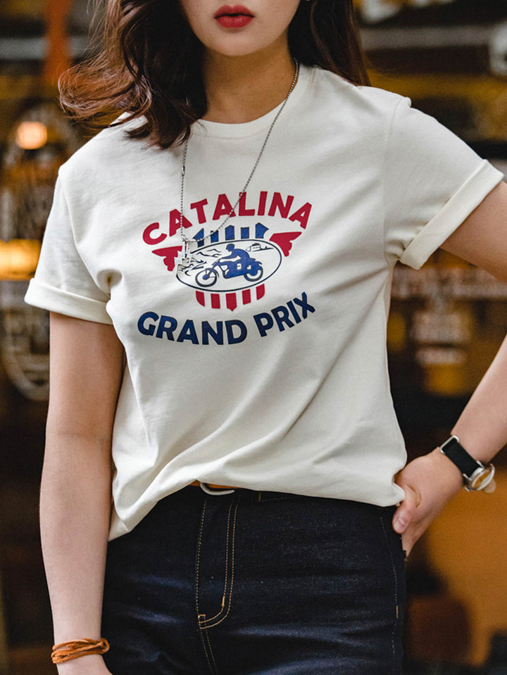 Tシャツ胸元の「Catalina Grand Prix」モーターサイクルレースのレトロプリントクローズアップ。モデルがカタリナ・グランプリ モーターサイクルレースプリントTシャツを着用し、カジュアルスタイルを披露。