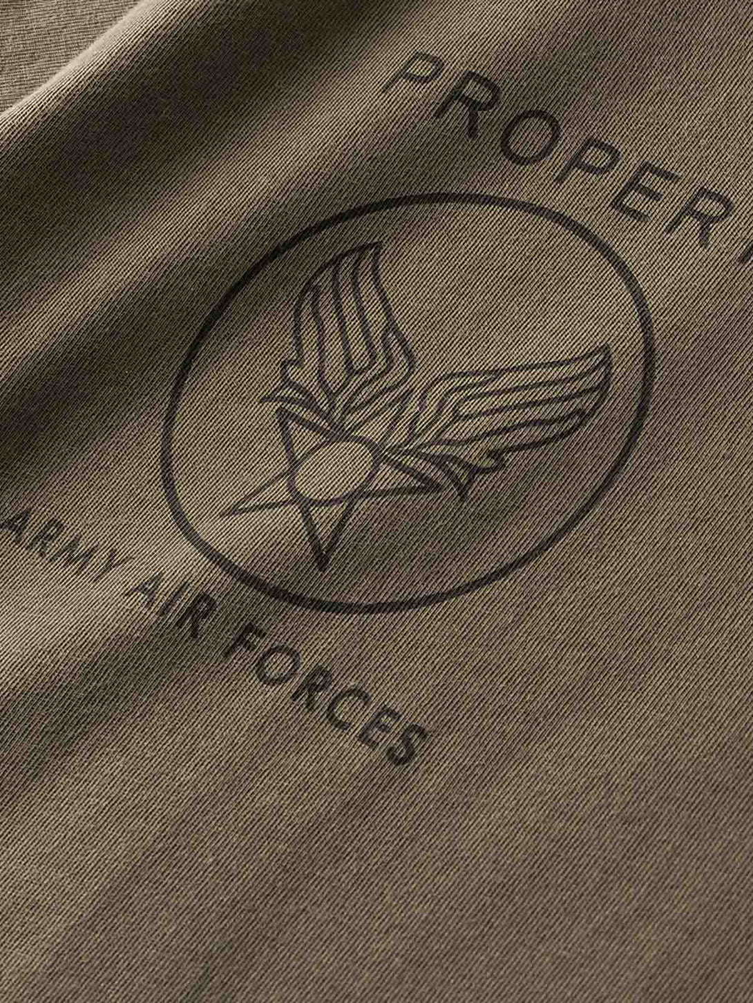 アメリカ空軍インスパイアードの半袖Tシャツの空軍バッジプリントのクローズアップ。彫印のプリント技法で施されたディテールが鮮明で、耐久性があり、衣服のプレミアムな感触を際立たせています。